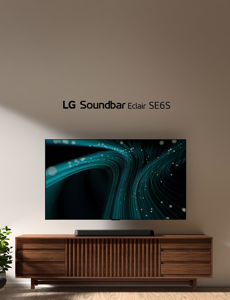 The LG Soundbar SE6S is placed on the wooden cabinet. Above a wall-mount TV with blue sound wave images and dotted lights is placed. On the left side a window is slightly seen and black leather leaning chair is placed in front of a green plant.
