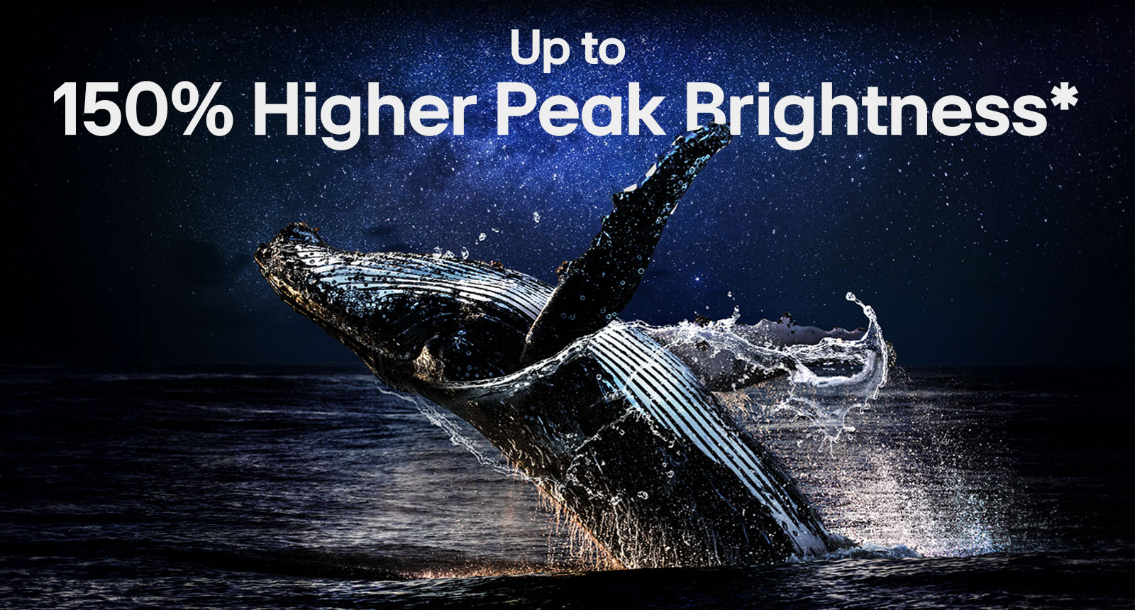 A video of a whale jumping out of the ocean against a black backdrop. The words "up to 150% brighter" appear above the whale and become brighter. The scene instantly brightens, revealing the Milky Way in the sky, bright markings on the whale, and glistening droplets of water.