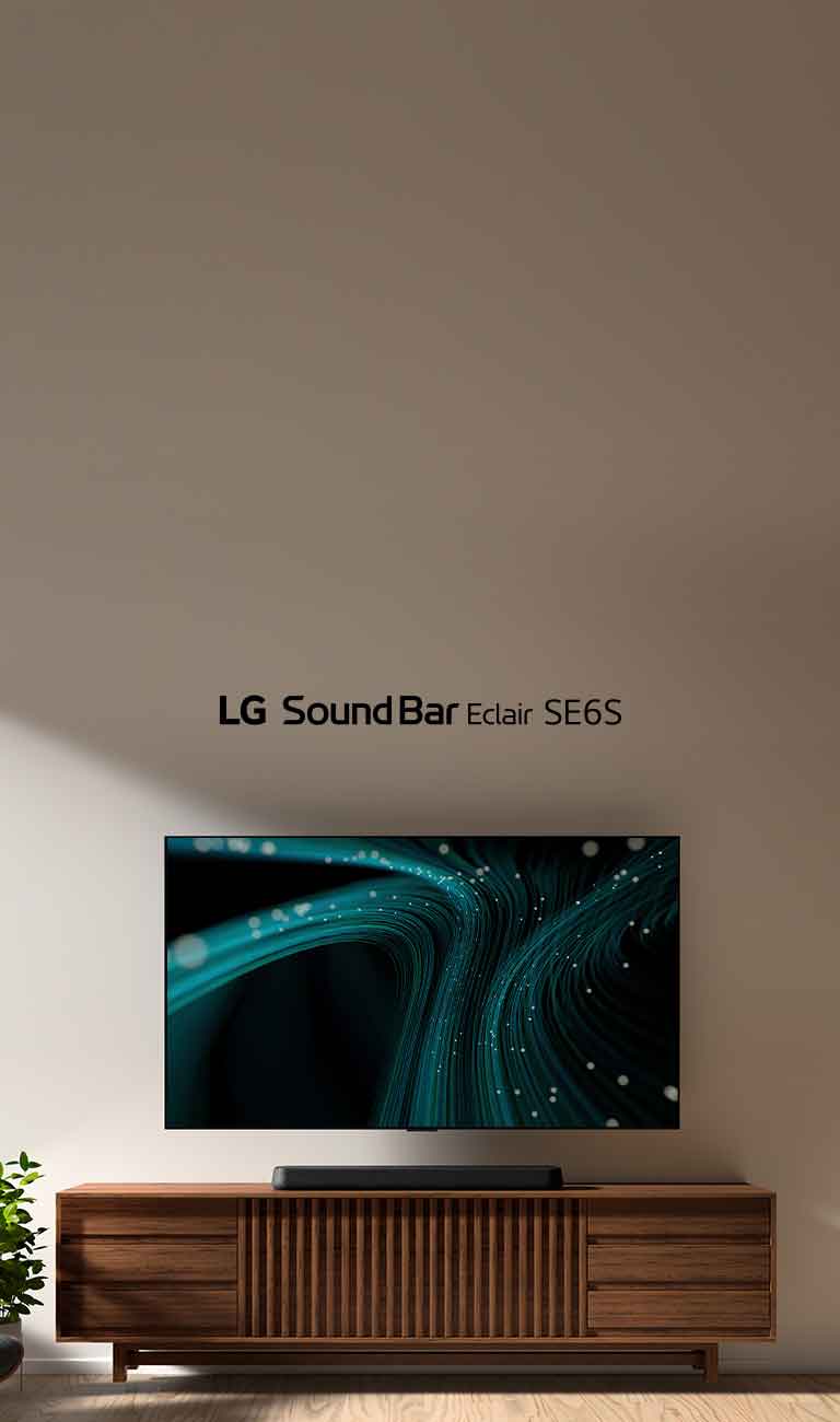 The LG Sound Bar SE6S is placed on the wooden cabinet. Above a wall-mount TV with blue sound wave images and dotted lights is placed. On the left side a window is slightly seen and black leather leaning chair is placed in front of a green plant.