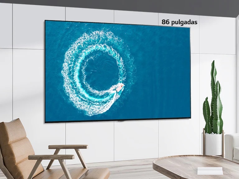 Comparación entre una pantalla de 55 pulgadas y una de 86 pulgadas, ambas colgadas en la pared, que muestran un bote haciendo una ola en el medio del océano.