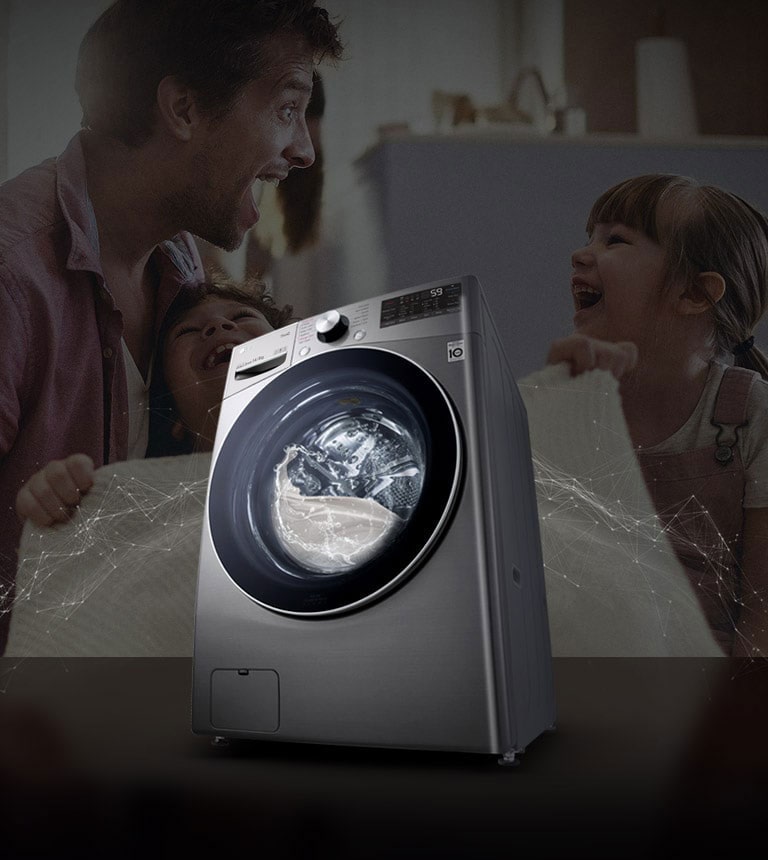 Pai e filhas riem em segundo plano enquanto seguram um cobertor limpo. Uma máquina de lavar branca com carregamento frontal está em primeiro plano.
