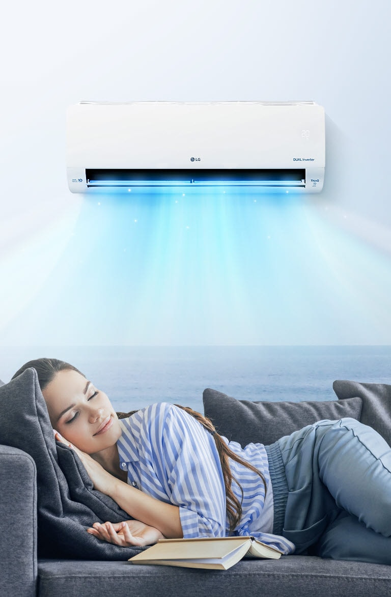 A woman rests comfortably on a couch with the air conditioner blowing air out over her.