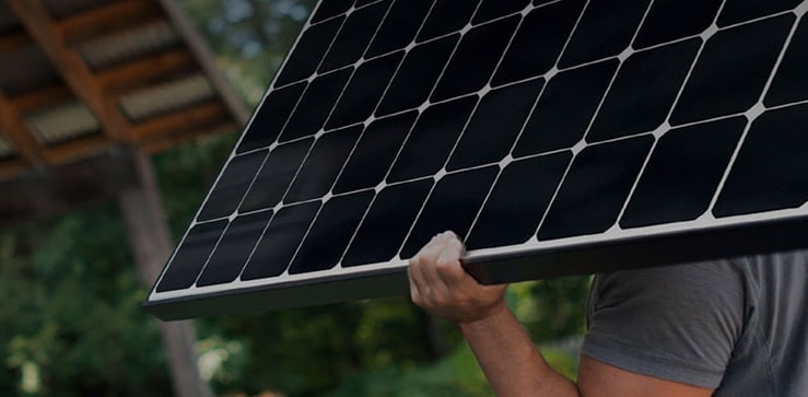 Ein Installateur trägt ein LG Solarmodul auf der Schulter