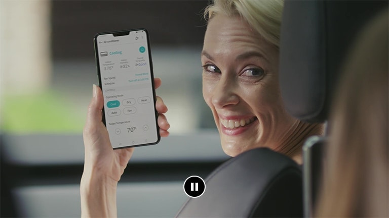 Eine in einem Auto sitzende Frau zeigt einer Person auf dem Rücksitz begeistert die App-Anzeige.