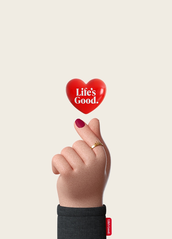 'A digital-style hand makes a finger-heart using the thumb and pointer finger, and above the gesture, a red heart shows LG's Life's Good logo.