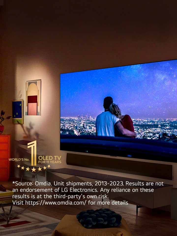 モダンで奇抜なニューヨーク市のアパートの壁に、LG OLED evo G3 が掛かっており、画面にはロマンチックなナイトシーンが映っている画像。 10 年間有機 EL テレビ 世界シェア No.1 エンブレム。 