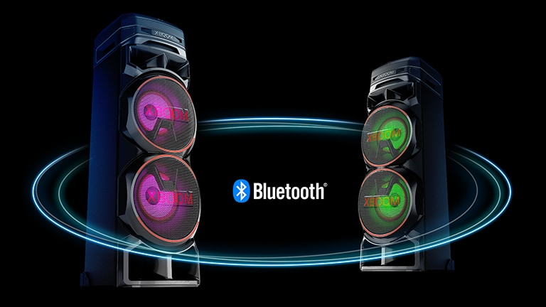 Dos RNC9 frente a frente en ángulos diagonales sobre un fondo negro con un logotipo de Bluetooth en el medio. Uno tiene luz violeta en el woofer y el otro tiene luz verde.