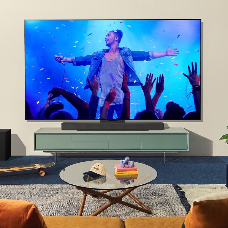 Una imagen muestra una casa moderna. El televisor y la barra de sonido se combinan con el soporte de sinergia.