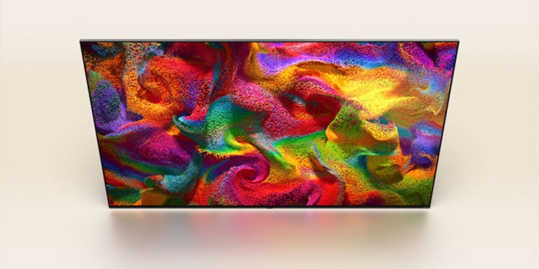 Las partículas de color estallan en la pantalla, luego los píxeles cambian lentamente a un primer plano de una pared pintada con un patrón colorido en la pantalla del televisor LG.