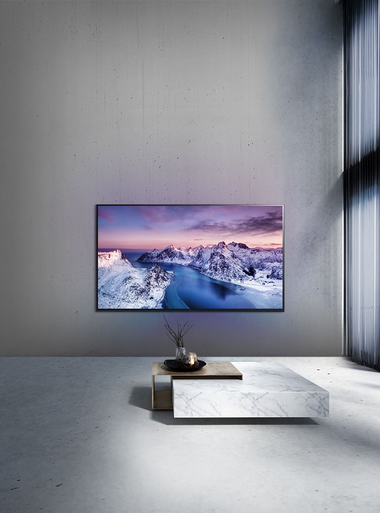 Un televisor UHD montado en la pared detrás de una mesa con ambientación de estilo zen.