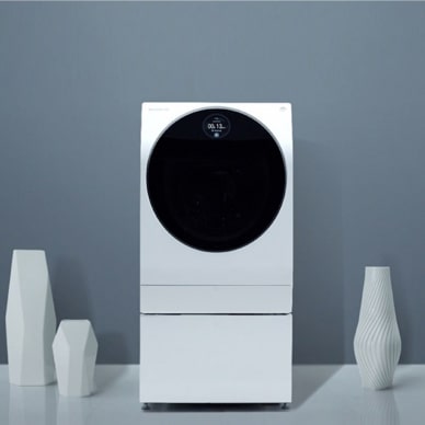 Eine weiße LG SIGNATURE Waschmaschine vor einem schlichten grauen Hintergrund mit dem Text „Emaille-Beschichtung“.