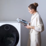 Vorschaubild von Olivia Palermo, die neben einem LG SIGNATURE Waschtrockner steht.