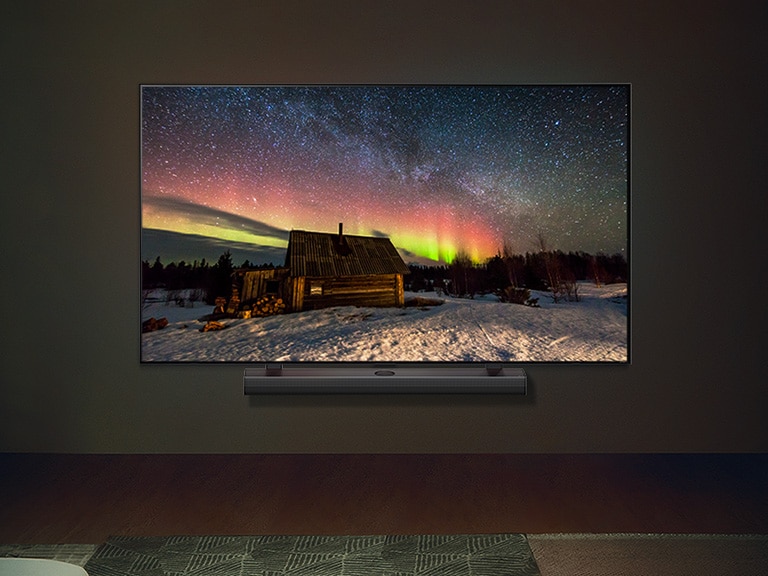LG TV og LG-soundbar i et moderne hjem om aftenen. Billedet på skærmen af nordlyset vises med ideelle niveauer af lysstyrke.