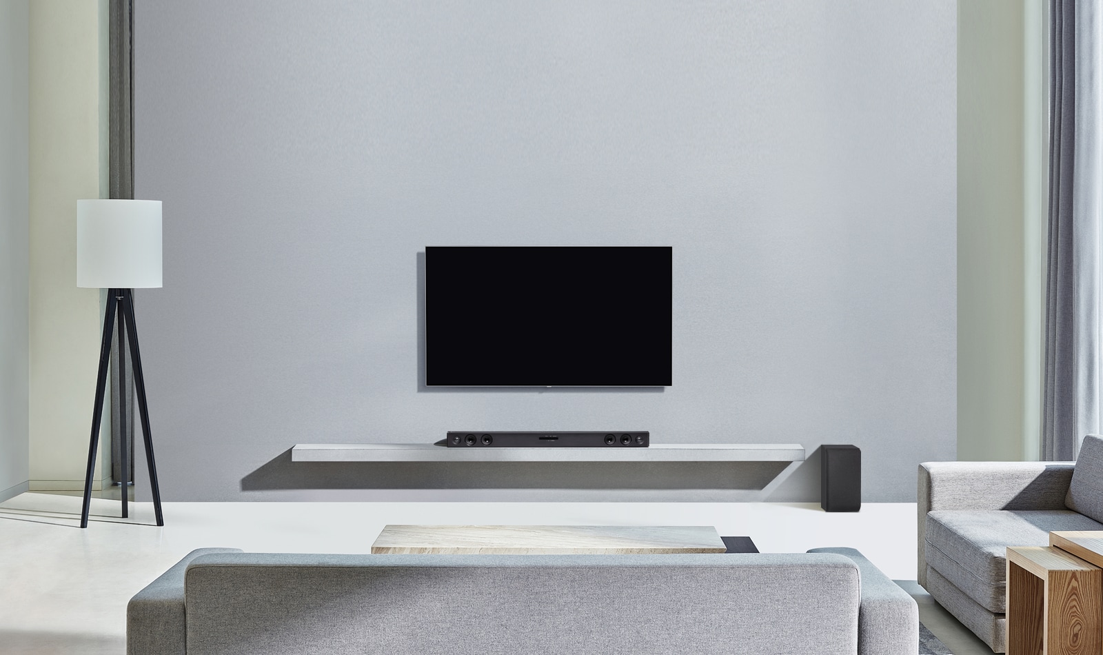 El televisor LG está colgado en la pared gris. Y la barra de sonido LG SQC2 está colocada en la estantería del salón. Y el subwoofer está colocado junto a la estantería. La imagen ilustra que la barra de sonido hace juego con el televisor LG y complementa la estancia.