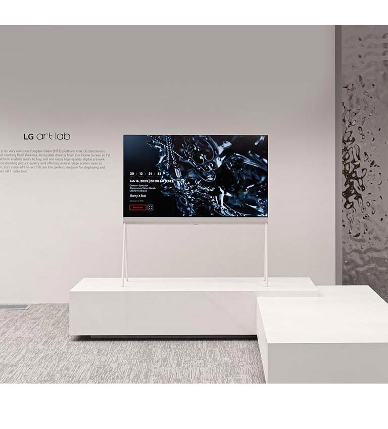 Una imagen de un televisor Easel en una habitación blanca que muestra en pantalla una escultura negra hecha con arte digital. La habitación se refleja en una escultura plateada ubicada a la derecha del televisor.