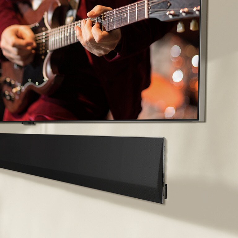 Vinossa kuvakulmassa alareunasta otettu kuva LG TV -televisiosta ja LG Soundbar -äänipalkista, jotka on kiinnitetty seinään.