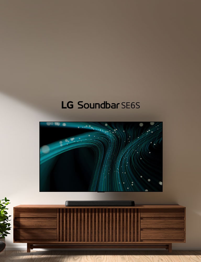 LG Sound Bar SE6S on puisen kaapin päällä. Sen yläpuolella on pistevaloja ja seinätelineessä oleva televisio, josta lähtee sinisiä ääniaallon kuvia. Vasemmalla puolella näkyy osittainen ikkunan, ja viherkasvin eteen on sijoitettu musta, nahkainen nojatuoli.