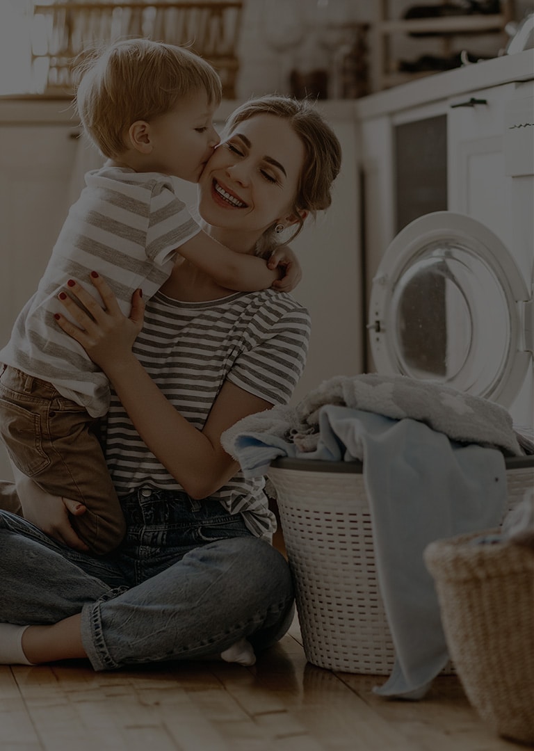 It's an image of a mother and a baby sitting in front of a washing machine.