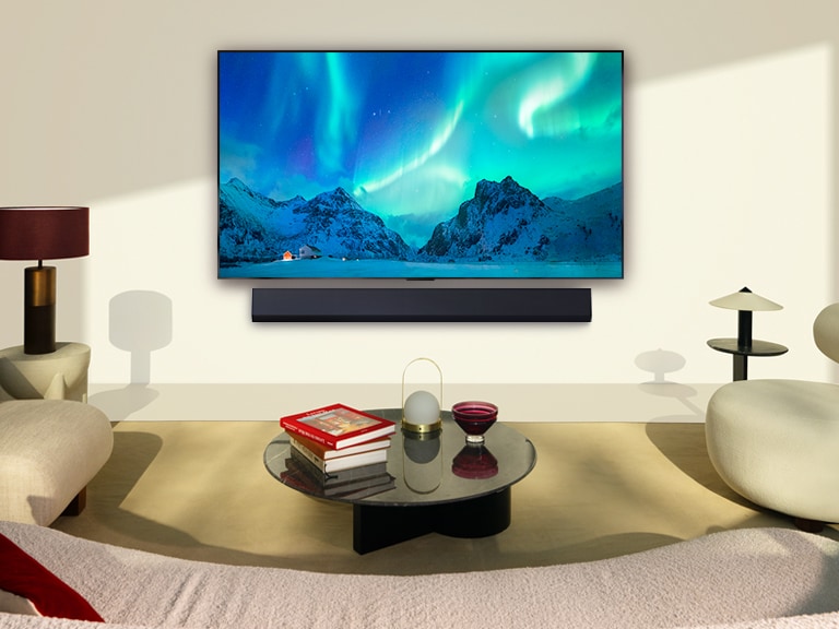 LG OLED TV i soundabr LG w nowoczesnej przestrzeni dziennej. Obraz zorzy polarnej wyświetlany jest z idealnym poziomem jasności.