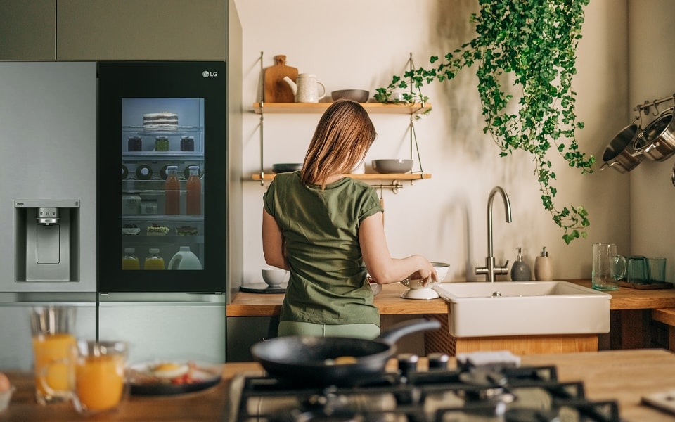 Uma mulher na cozinha com um frigorífico transparente