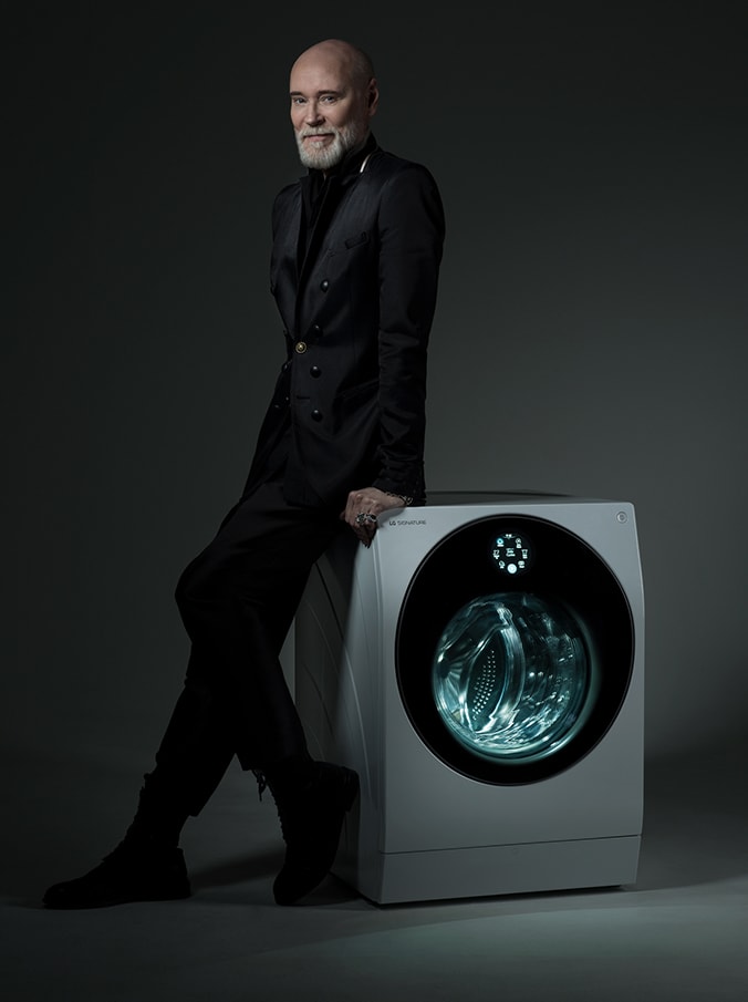 Modeskaparen Lars Wallin lutad mot en LG SIGNATURE tvättmaskin, med has namnteckning skriven på bilden