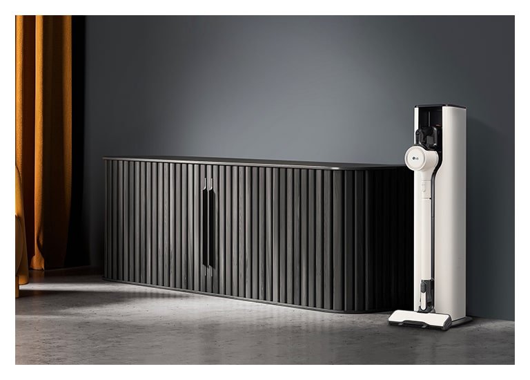 顯示雪霧白色的 LG CordZero All-in-One 濕拖無線吸塵器 Objet Collection 放置在深色調的客廳內。