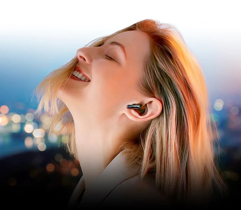 Позаду тексту «Прослуховування по-новому» жінка в навушниках TONE Free занурена в музику на фоні нічного міста.