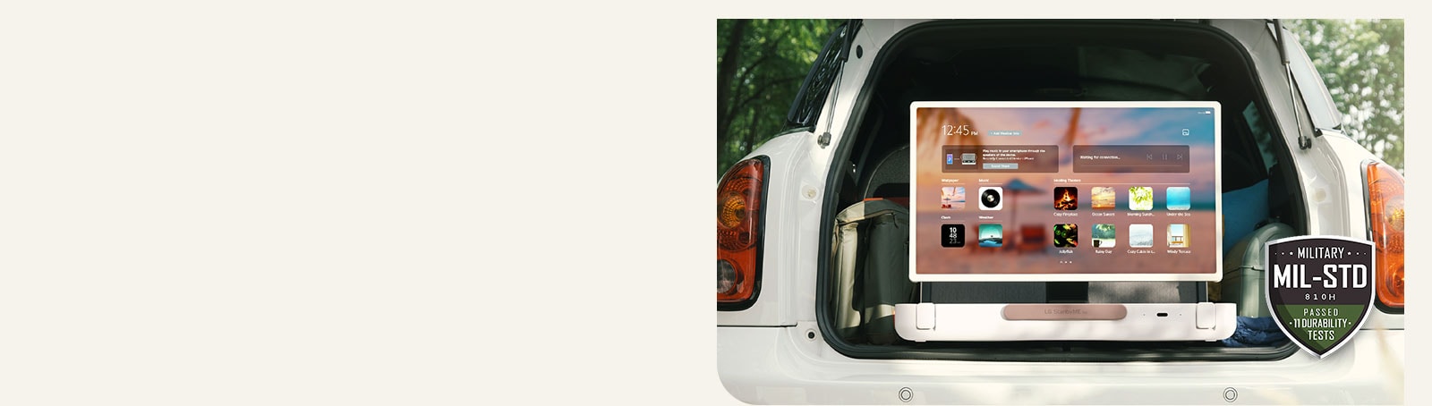 Mặt trước của LG StanbyME Go. Sản phẩm được đặt trên ô tô, màn hình xoay ngang hiển thị màn hình chính. Ở phía dưới bên trái của hình ảnh, biểu tượng thông số quân sự được hiển thị.