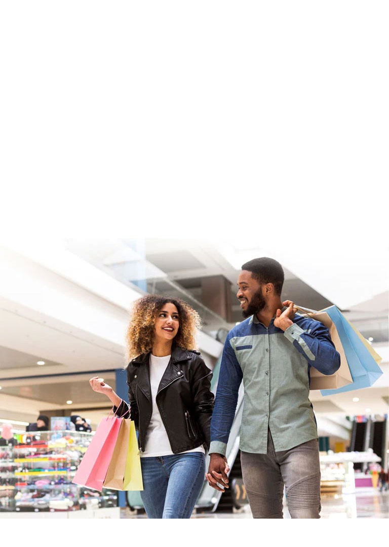 A couple shopping at a mall with colorful shopping bags.