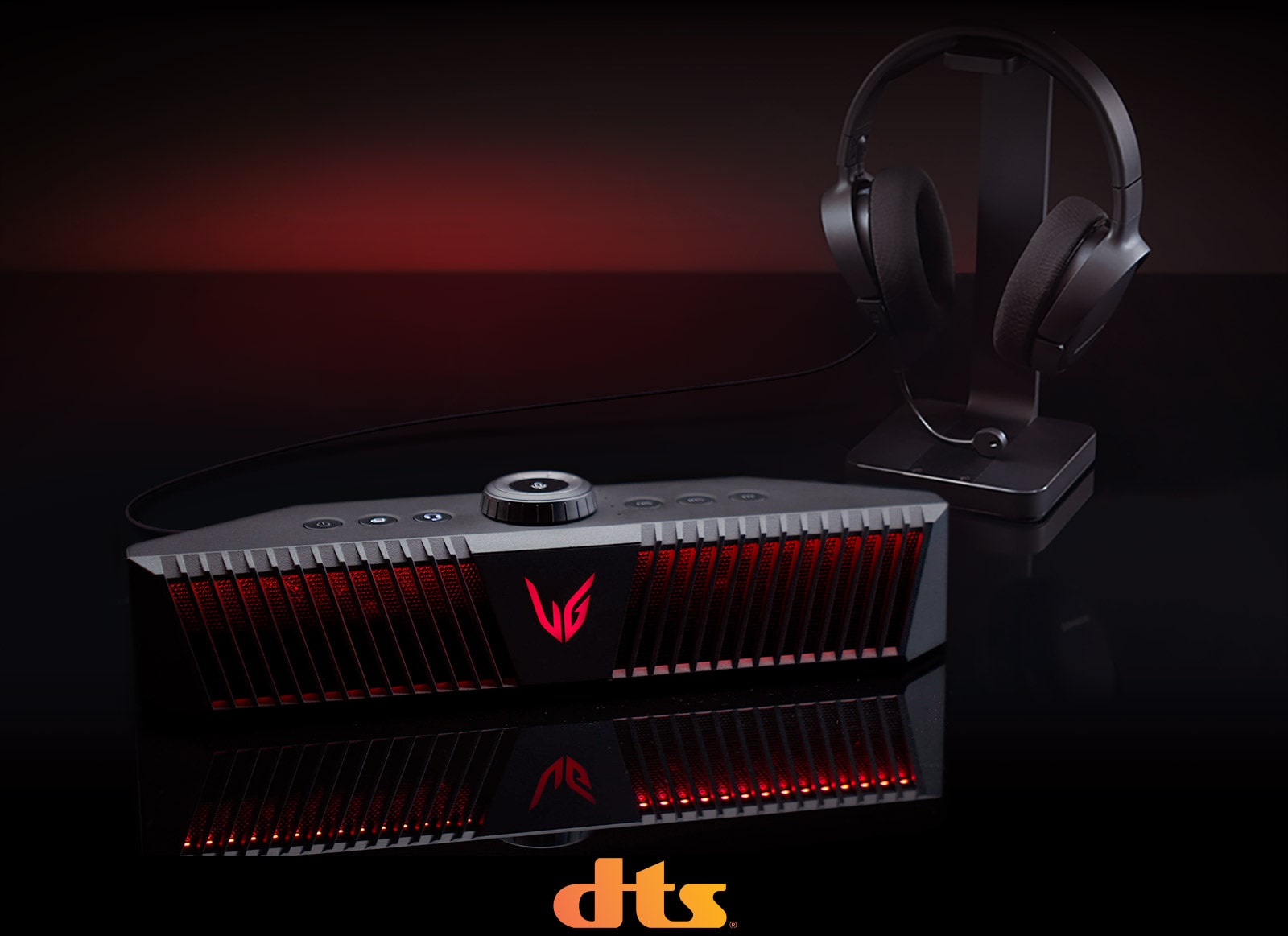 A gaming speaker is placed on black desk and there is a headset placed right behind - a DTS logo is placed on bottom center of image.