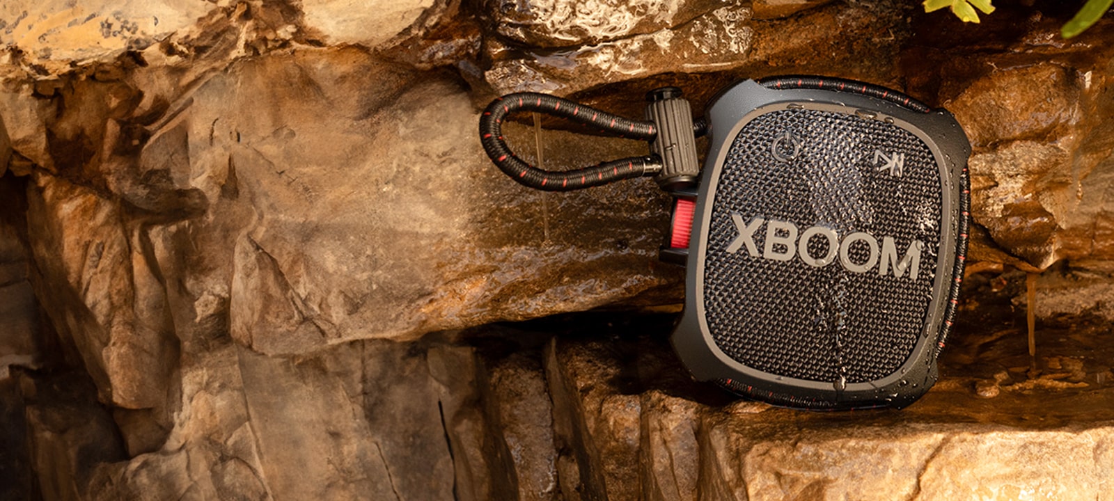 A man sitting on the floor and liesting music with LG XBOOM Go XG2T hagging on his backpack.