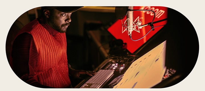will.i.am is working in studio looking at a screen placed below a mic.