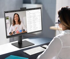 A woman wearing a headset is video conferencing with the built-in webcam.	