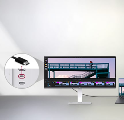 A USB Type-C cable connected between a laptop and an ultra-wide LG monitor displaying a video editing interface, with a close-up showing the USB-C port on the monitor.	