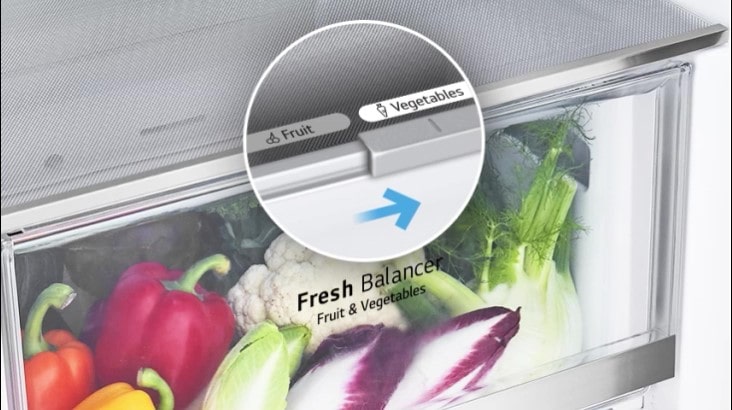 The bottom drawers of the fridge are filled with colorful fresh produce. An inset image magnifies the control lever to choose the optimal humidity level to keep produce fresh.