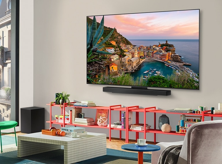 In a colorful living room is a wall-mounted LG OLED TV with Soundbar. The perspective is at an angle showing the ultra slim frame of the TV against the wall. 