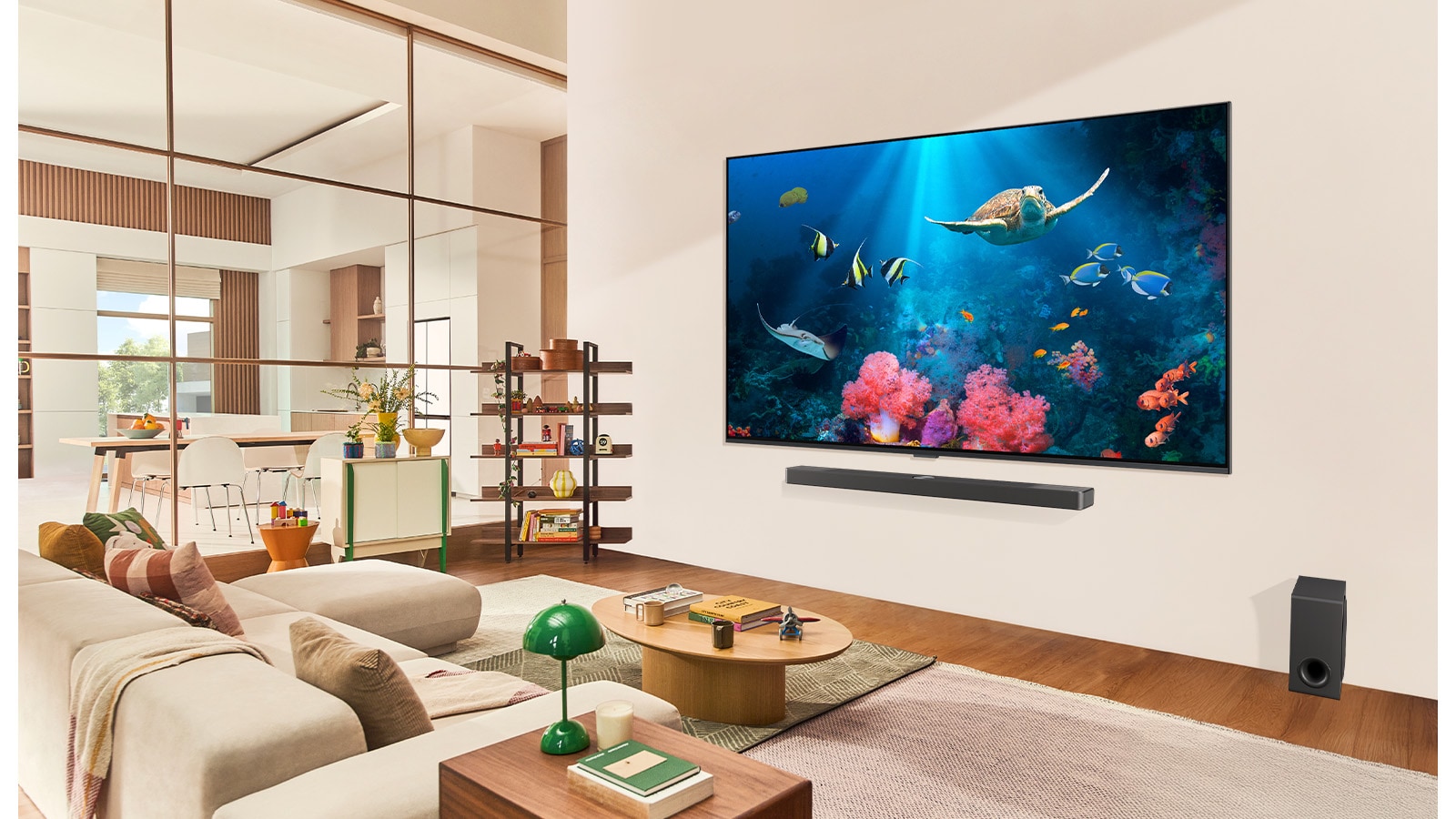 A family in a living room with an ultra big LG TV mounted on the wall, with an ocean scene including coral and a turtle on the screen.
