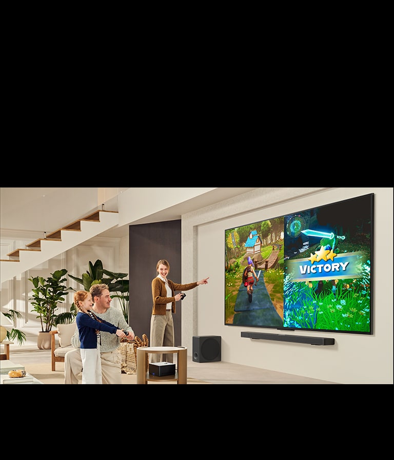 Family of 3 playing a game in a living room with a LG TV mounted on a wall above a LG Soundbar. Zero Connect Box sits inside a coffee table.