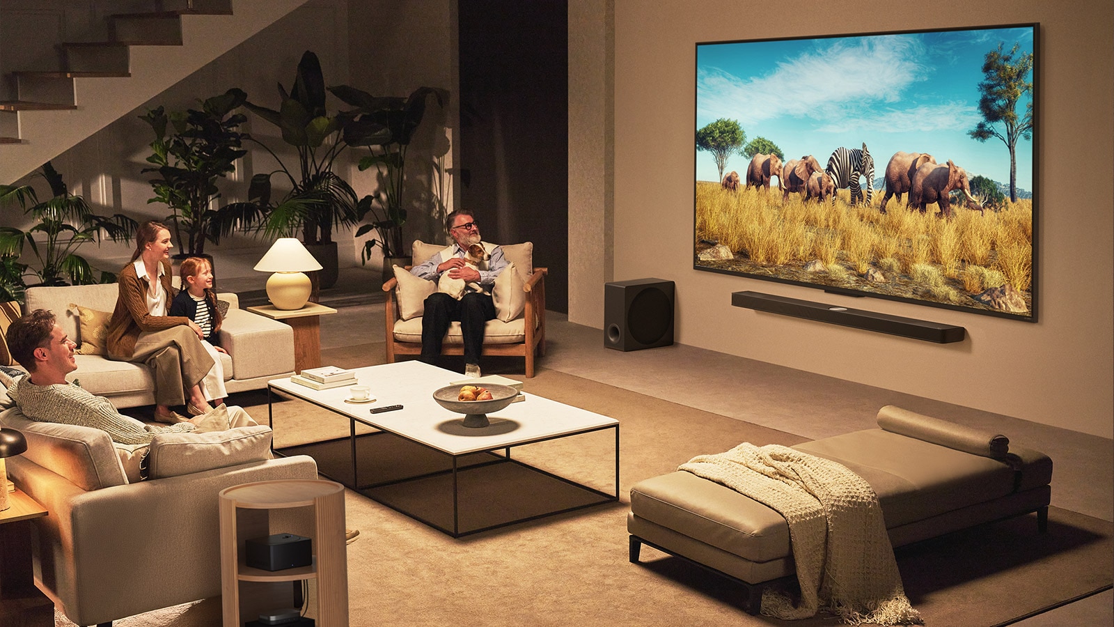 A family sits on a couch facing a LG QNED TV mounted on a wall above a LG Soundbar in a modern living room space.  Zero Connect Box sits inside a coffee table.