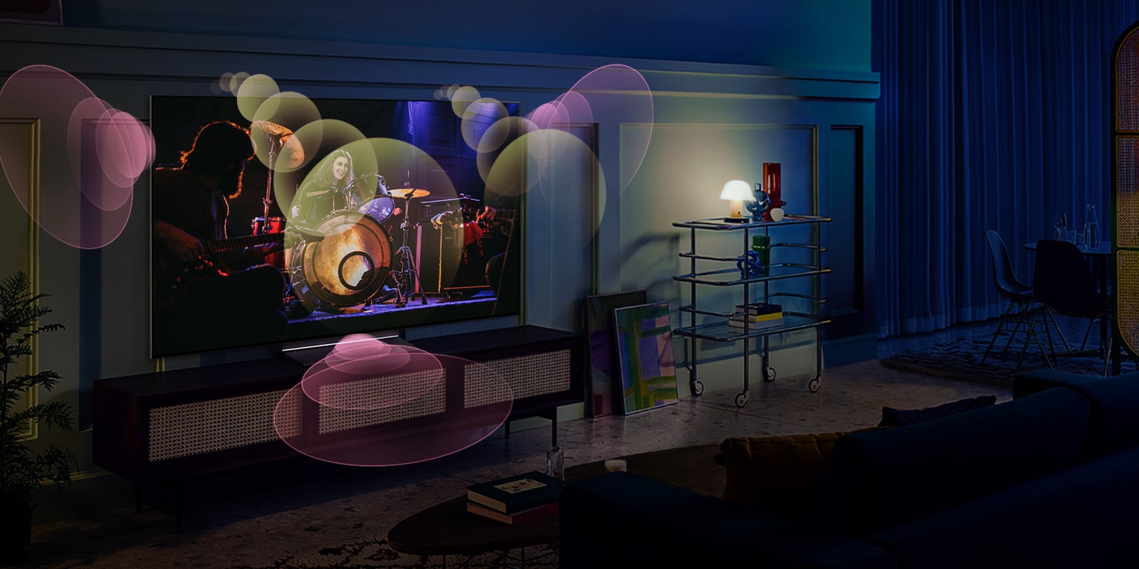 People sit on a couch watching a concert with bubbles depicting surround sound around them.