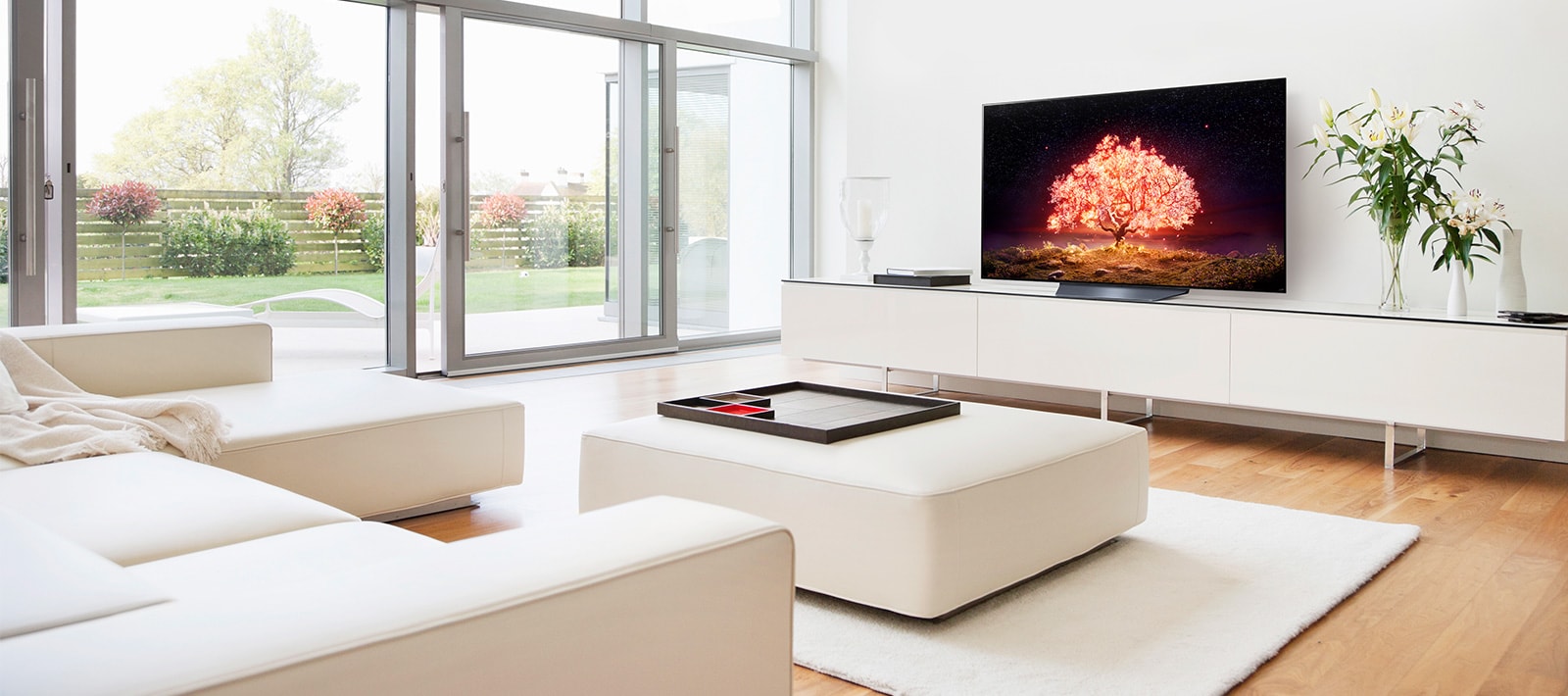 A TV showing a tree emitting red light in a white and simple house setting