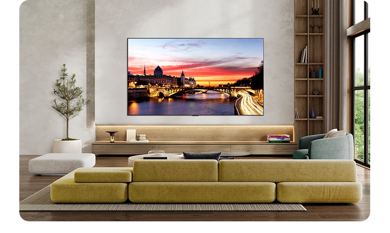 LG OLED evo AI C6 is wall-mounted in a styled living space, featuring an ultra-slim design with narrow bezels, and it displays a riverside cityscape at sunset on screen. 