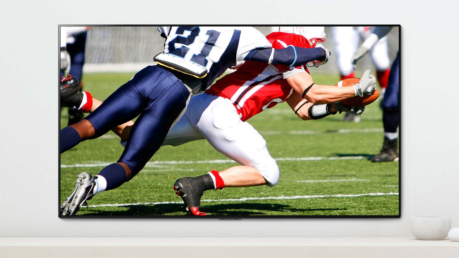 A scene of a sports game showing two men who are playing dynamically playing American football on a TV screen