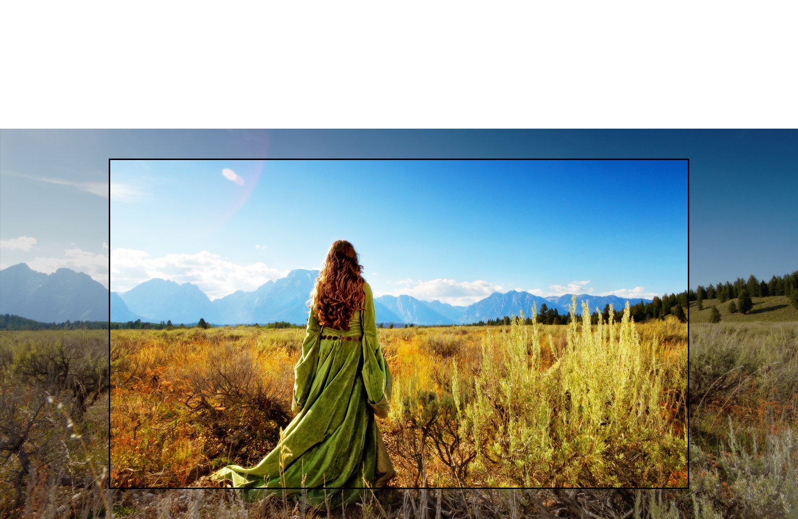 A TV screen showing a scene from a fantasy movie with a woman standing in the fields facing the mountains.