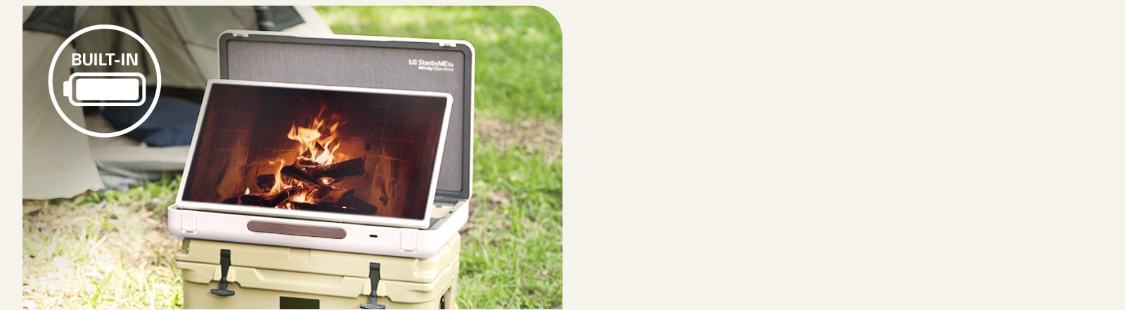 The LG StanbyME Go is placed in front of a tent, and the screen displays one of the relaxing themes--a fireplace. On the left top corner, built-in battery icon is shown.