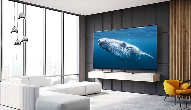 In a living room, there is a large screen TV displaying an image of a big whale in the sea.