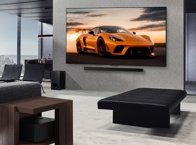 Spacious living room with a view of a cityscape. LG OLED TV is mounted on the wall with an LG Soundbar. The TV's Ultra Slim Design is showcased. Zero Connect Box is visible, but concealed.