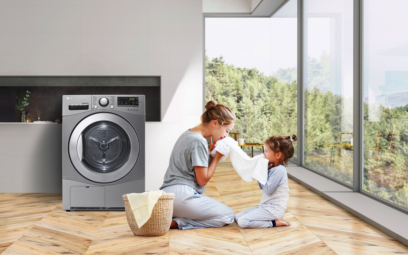 A mother and daughter sit on the floor holding and enjoying the smell of a towel that just came out of the Condensing Type Dryer that sits next to them.