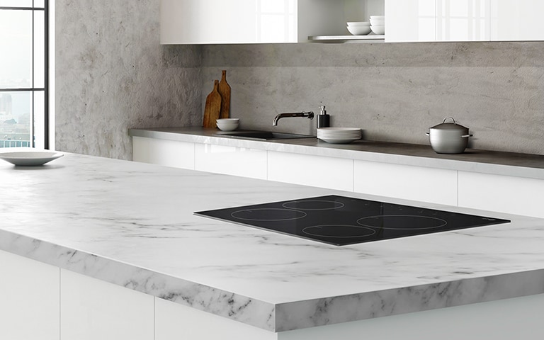 The STUDIO cooktop is installed in a kitchen island in a modern white kitchen.
