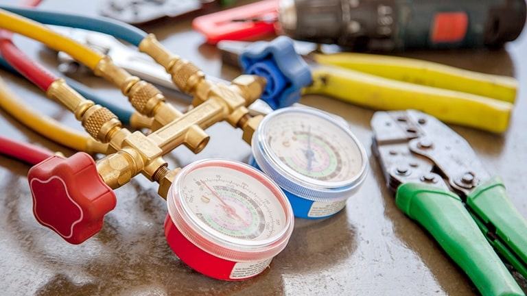 A pressure transmitter, red and blue gauges linked to multicolored hoses take center stage, with various tools neatly arranged to the right.